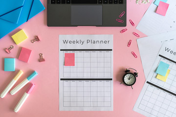 Laptop, stationery and planner on pink pastel background
