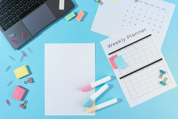 Laptop, stationery and planner on blue pastel background