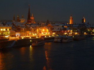 Fototapeta premium Würzburg Panorama im Winter mit Schnee bei Nacht. Uferpromenade bei Nacht mit altem Kran 