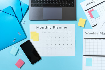 Smartphone, laptop, stationery and planner on blue pastel background
