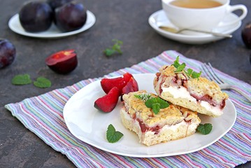 Sliced shortbread cake with curd cream and plum on a white plate. Sweet cakes. Harvest plums.