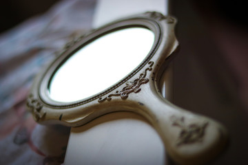 Wood carved, white hand held mirror shot at the dutch angle with focus in central frame and...