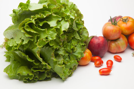 Lechuga verde y distintas frutas, tomates, cherri y de los otros, nectarinas todo sobre fondo blanco
