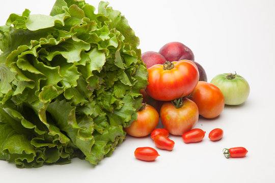 Lechuga verde y distintas frutas, tomates, cherri y de los otros, nectarinas todo sobre fondo blanco