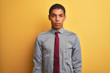 Young handsome arab businessman wearing shirt and tie over isolated yellow background Relaxed with serious expression on face. Simple and natural looking at the camera.