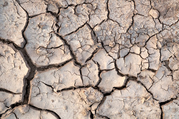 Cracked soil during a drought. Deep cracks in the land. The texture of the earth during drought. View from the top.