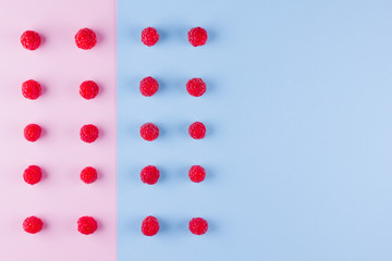 Pattern of raspberries on pink blue background. Colorful diet and healthy food concept. Background of raspberries. Top view. Flat lay. Copy space