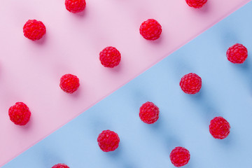 Pattern of raspberries on pink blue background. Colorful diet and healthy food concept. Background of raspberries. Top view. Flat lay. Copy space