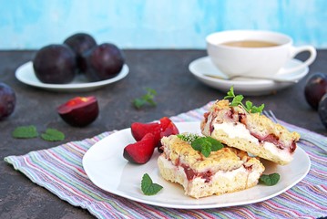 Sliced shortbread cake with curd cream and plum on a white plate. Sweet cakes. Harvest plums.