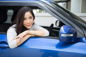 Asian woman sitting in a blue car