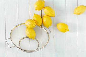 Pile of lemons in colander on a wooden table top view