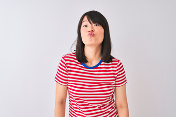 Young beautiful chinese woman wearing red striped t-shirt over isolated white background looking at the camera blowing a kiss on air being lovely and sexy. Love expression.