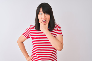 Young beautiful chinese woman wearing red striped t-shirt over isolated white background Looking fascinated with disbelief, surprise and amazed expression with hands on chin