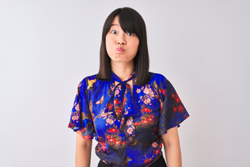 Young beautiful chinese woman wearing summer floral t-shirt over isolated white background puffing cheeks with funny face. Mouth inflated with air, crazy expression.