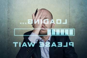 businessman or office worker waits bored and long on his slow computer or internet connection, displaying a loading bar and a message