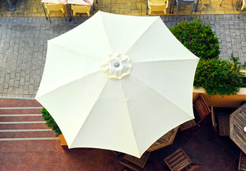 White umbrella seen from above on the terrace of a beach bar