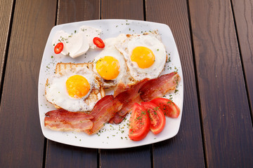 Healthy bacon fried egg on toast bread breakfast on plate , fresh tomatoes and cheese on plate , wood background.