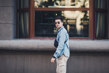 stylish man with a bag of denim clothes in the city