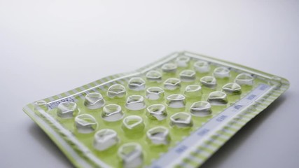 Empty package of birth control pills falling in slow motion. The used blister packet of oral contraceptives represents women's rights, reproductive issues and the affordable care act.
