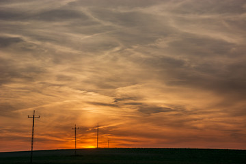 Obraz premium Electric poles in the field, sky and clouds after sunset