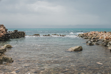 Stony seashore - large stones in the foreground - a beautiful seascape - the ruins of a marine fortification
