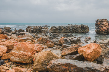Stony seashore - large stones in the foreground - a beautiful seascape - the ruins of a marine fortification