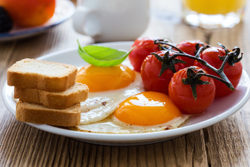  Fried eggs with cherry tomatoes, fresh summer fruits, berries, coffee and juice