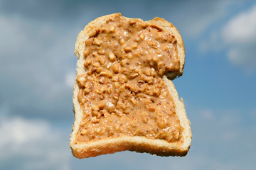 Crunchy Peanut Butter on toast with sky background - idyllic spread on toast snack concept.