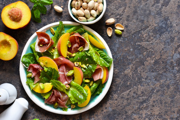 Fresh prosciut salad with peppers and pistachios on a concrete background. View from above.