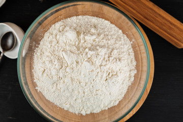 Making dough for pizza, flour in glass bowl on wooden cutting board, top view