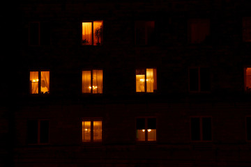 Illuminated in the dark of the night the windows of the houses of an apartment house