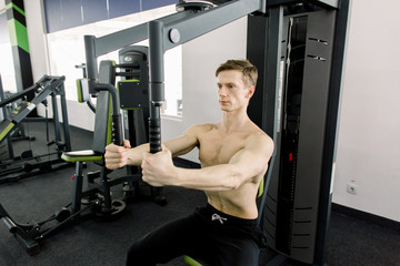 Bodybuilder posing in the gym. Handsome muscular man working out hard at gym. Training without shirt. Chest exercises. Chest workouts.