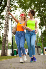 Two girlfriends walking on summer park, outdoors