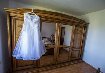 Fototapeta na wymiar A white wedding bride dresses hanging on an old wooden wardrobe with mirrors