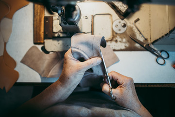 Close up shot of old shoemaker in his store. Traditional way of shoe making process.