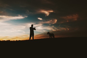 Fototapeta premium silhouette of man and dog on top of mountain