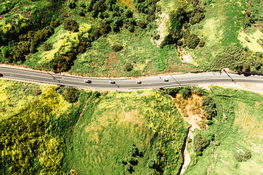 Aerial view of cars driving on road through green landscape