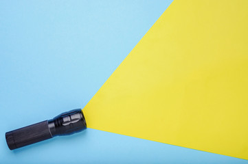 Flashlight on a blue background with a yellow ray of light, made from paper with empty space for text. Top view