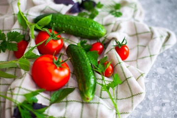 Fototapeta na wymiar Tomatoes, cucumbers, basil and parsley on kitchen towel.