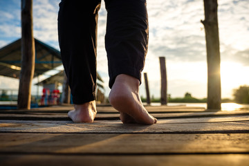 Bare Feet Step on Wood Pier at Sunset
