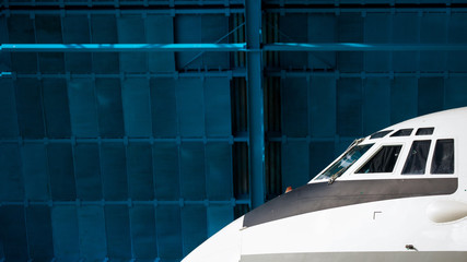 The nose of the aircraft against the blue hangar. Front portholes