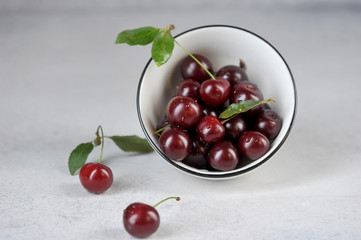 Ripe berries of sweet cherry in a white bowl. Light background.