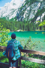 man with backpack looking at lake in dolomites mountains