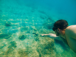 man swimming underwater with mask holding breath