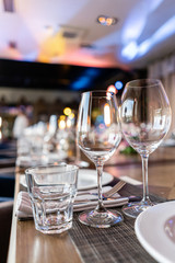 Wine glasses in the foreground. Wedding Banquet or gala dinner. The chairs and table for guests, served with cutlery and crockery.