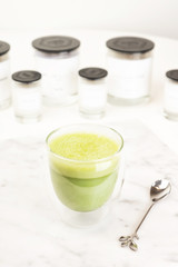 Glass cup of Hot art matcha Latte Coffee on white table in Coffee shop. Sweet rose drink with milk