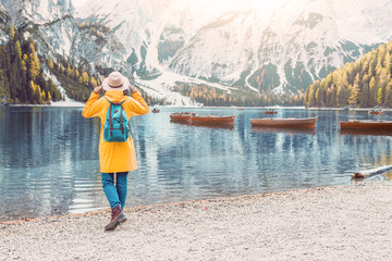 Traveling woman with backpack looking at the mountain lake Braies in Alps