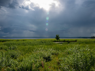 Fototapeta na wymiar Storm clouds rolling in over peaceful lake,wonderful reflections, Lake Burtnieks, Latvia