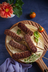 Lamb kebabs on serving board with pita bread, vegetables and yogurt sauce. View from above, top studio shot