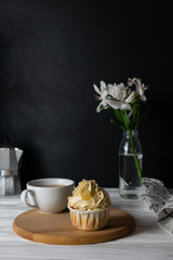 Tasty cupcake with almond flavor frosting with cup of coffee